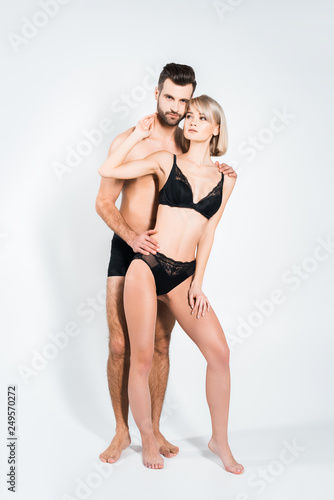 handsome boyfriend and beautiful girlfriend hugging in black underwear on grey