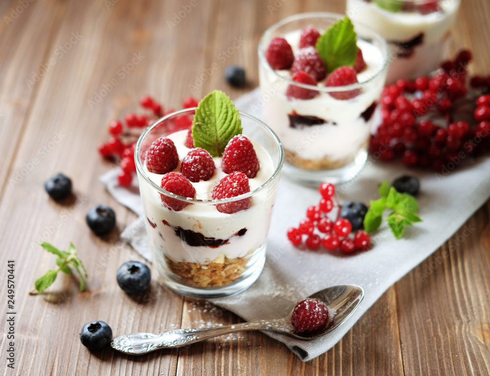 Healthy breakfast - yogurt with fresh berries and muesli served in glass jar, on wooden background Healthy breakfast - yogurt with fresh berries and muesli served in glass jar, on wooden background