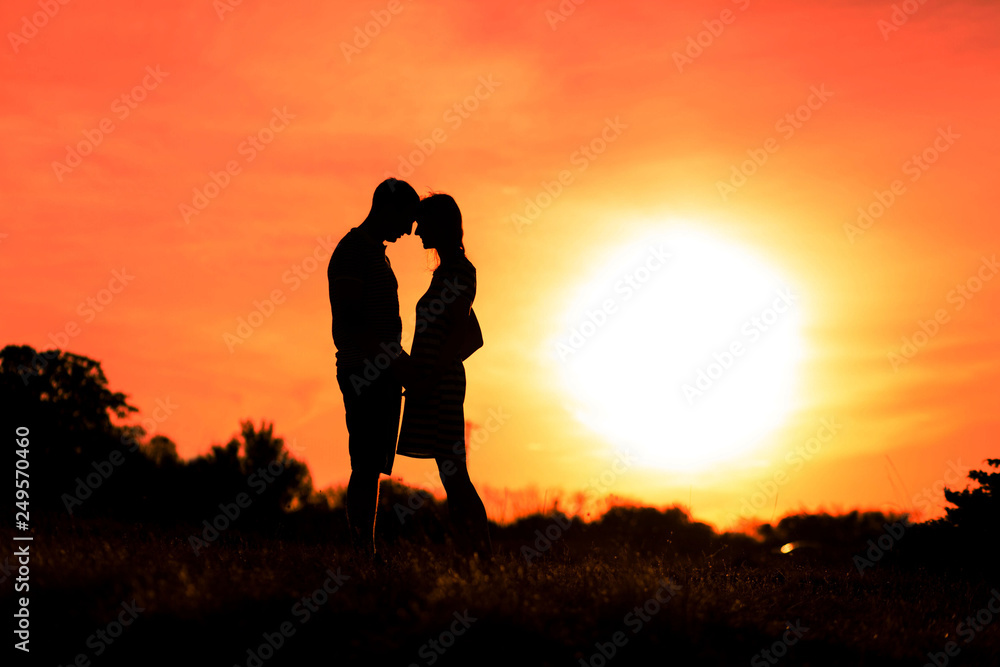 Girl and boy are hugging on a sunset sky background