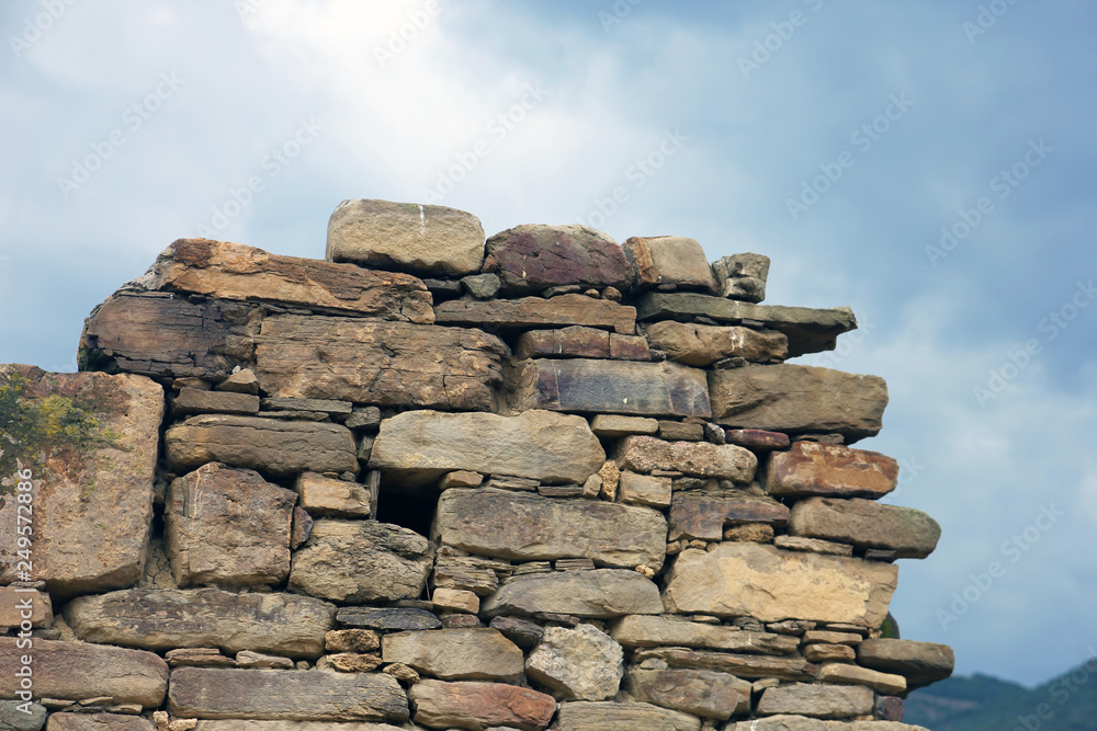old ancient ruined stonework wall of bricks and stone blocks foreground closeup green mountains background old ancient ruined stonework wall of bricks and stone blocks foreground closeup green mountains background