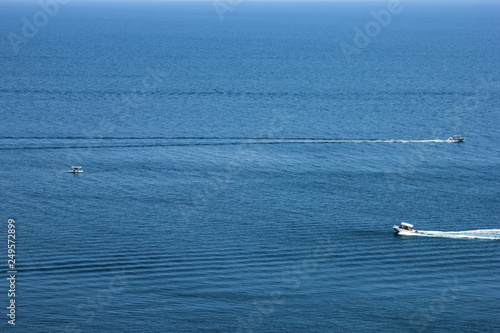 best blue sea in full screen and small ripples on the water and two motor boats cross the water surface