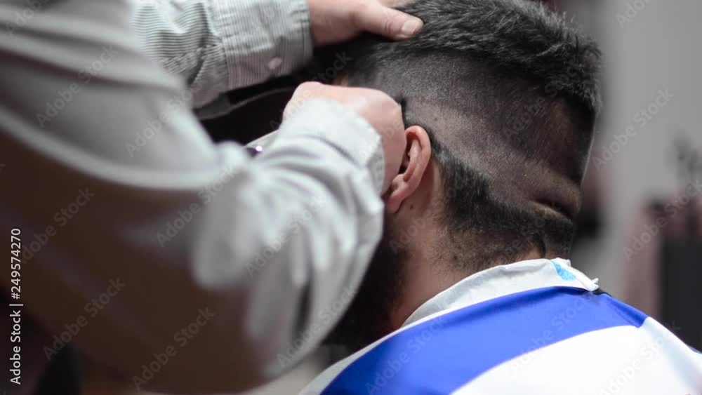 Handsome bearded man getting haircut by hairdresser at the barber shop . Handsome bearded man getting haircut by hairdresser at the barber shop .