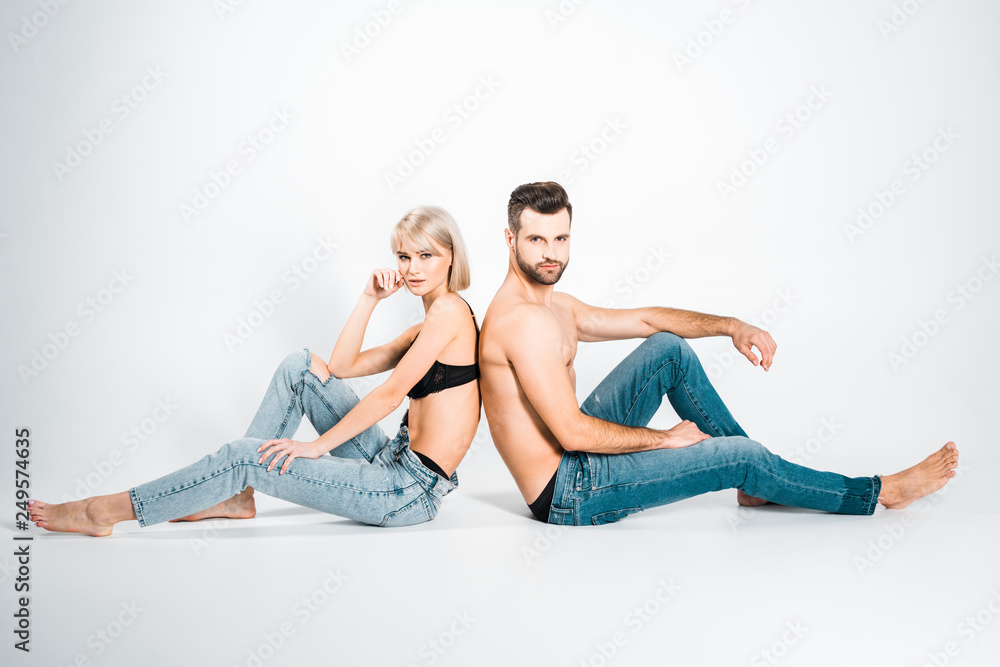 beautiful girlfriend and handsome boyfriend in underwear and jeans sitting back to back on grey beautiful girlfriend and handsome boyfriend in underwear and jeans sitting back to back on grey