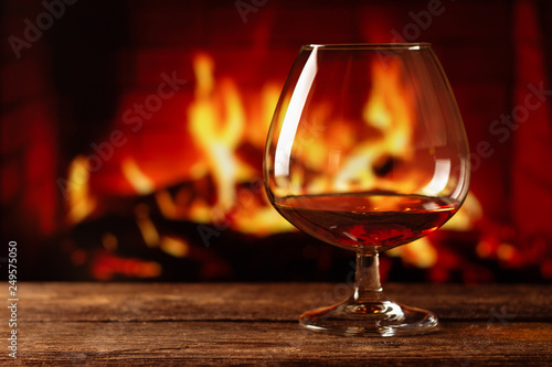 A glass of cognac on wooden table with bonfire background