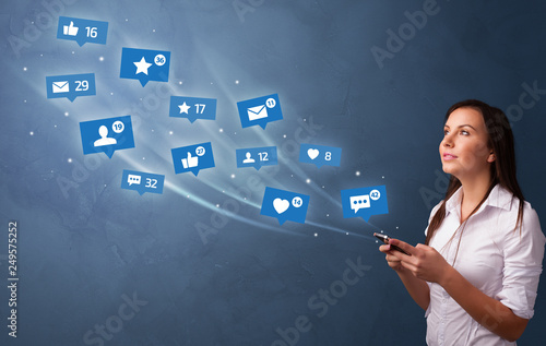 Young person using phone with flying social media icons around
