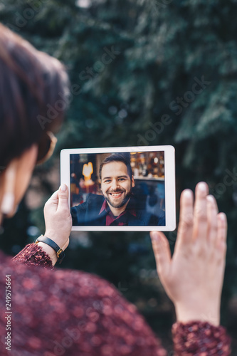 Young woman using a tablet by having a video call chat with her businessman boyfriend who is away on a business trip. Concept of keeping a long distant relationship in a career oriented world. photo