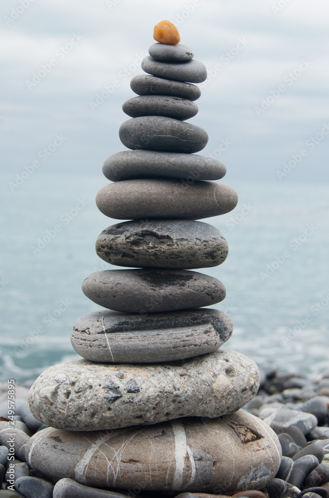 Gray stones in equilibrium on the beach in front of a stormy sea and sky of Camogli Gray stones in equilibrium on the beach in front of a stormy sea and sky of Camogli
