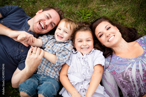 Happy Young Family Lying in Grass Together Outside