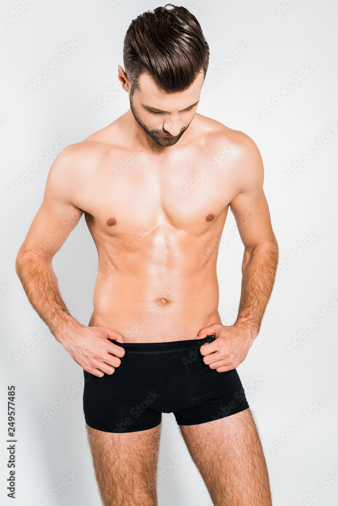 handsome muscular man in black underwear posing isolated on grey