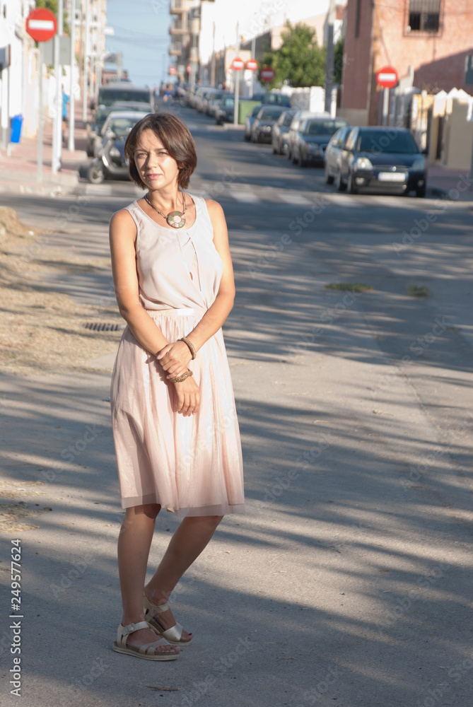 City chic young woman wearing pink dress on street.