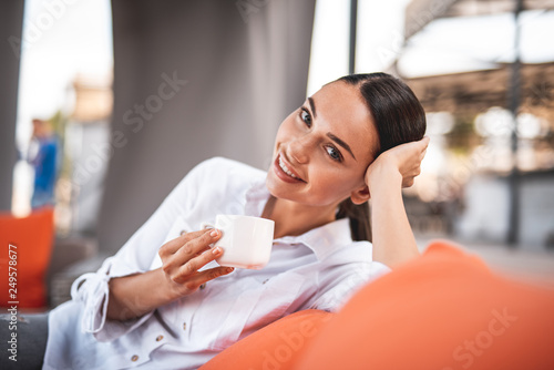 Close up of cheerful lady drinking coffee and relaxing