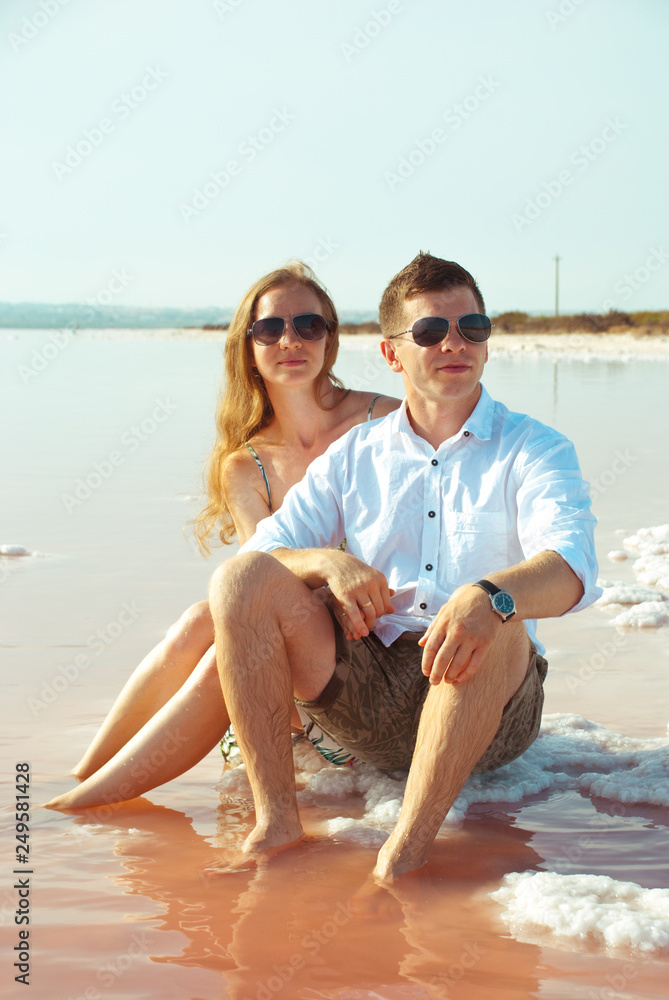Couple of lover looking in the same ahead. Happy famile siting on beach of lake. Romantic man and woman. Couple of lover looking in the same ahead. Happy famile siting on beach of lake. Romantic man and woman.