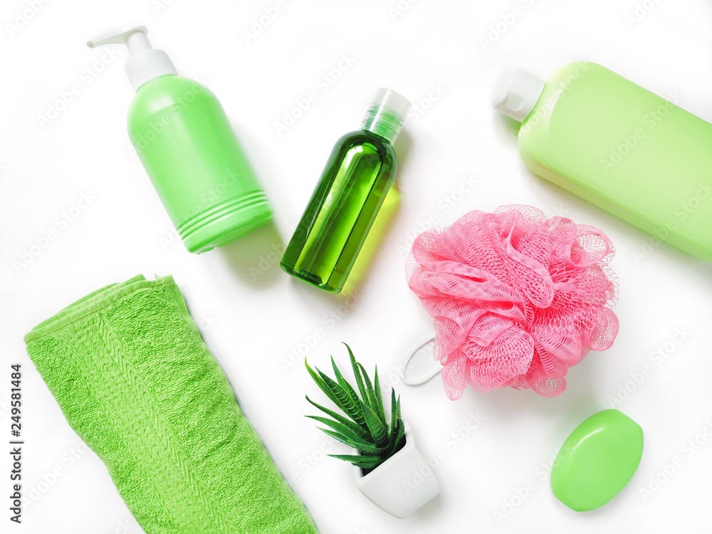 Green liquid soap, essential oil, shampoo, rolled cotton towel, pink sponge. Flat lay herbal organic natural bath products and spa cosmetics for skin, hair care Green liquid soap, essential oil, shampoo, rolled cotton towel, pink sponge. Flat lay herbal organic natural bath products and spa cosmetics for skin, hair care