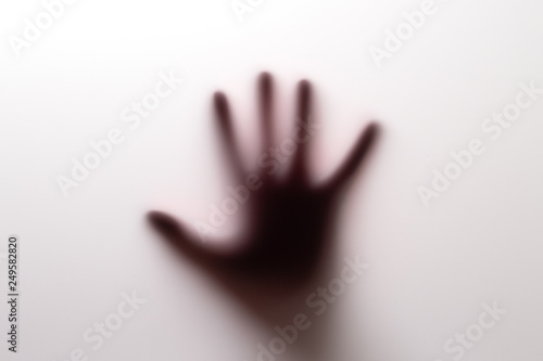 Shadow of hand behind glass.