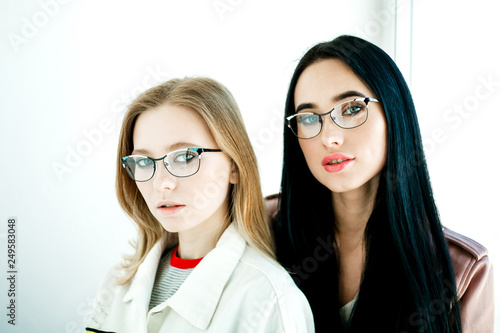 Two women with glasses on a white background. Concept photo for advertising glasses.