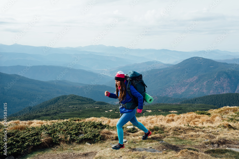 Young woman hiker with backpack walking a trail in rocky mountains