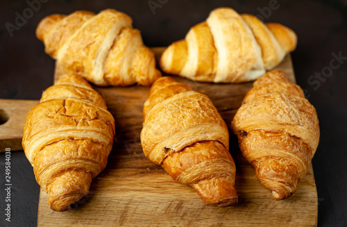 croissants on wooden cutting board, on background  stone, top view