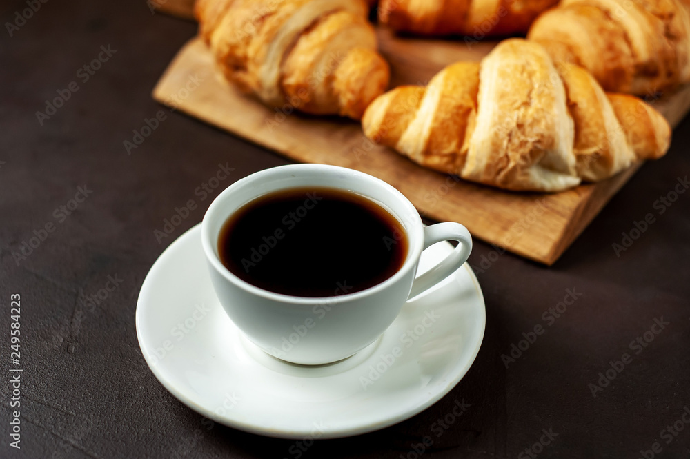 coffee and croissants on wooden cutting board, on the background concrete coffee and croissants on wooden cutting board, on the background concrete