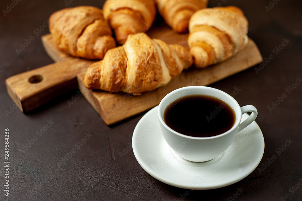 coffee and croissants on wooden cutting board, on the background concrete coffee and croissants on wooden cutting board, on the background concrete