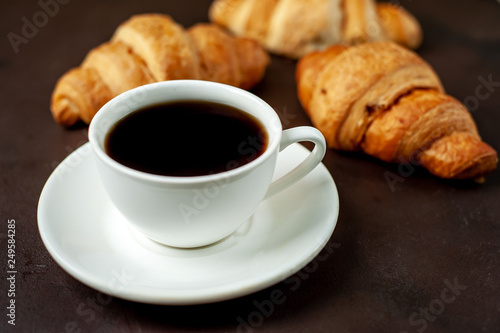 coffee and croissants on wooden cutting board  on the background concrete
