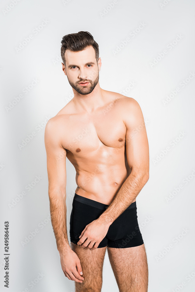 handsome man in black boxer shorts posing isolated on grey