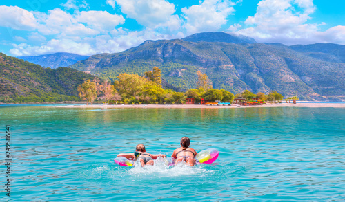 Fototapeta Naklejka Na Ścianę i Meble -  Girls in bikini lying on air bed in the turqouise sea - Oludeniz Beach And Blue Lagoon, Best beaches in Fethiye, Turkey 