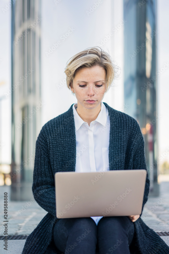 Young businesswoman sitting on stairs, using laptop Young businesswoman sitting on stairs, using laptop