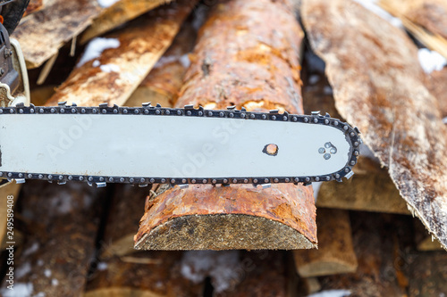 A chainsaw guide bar over the wooden board or  chainsaw in action