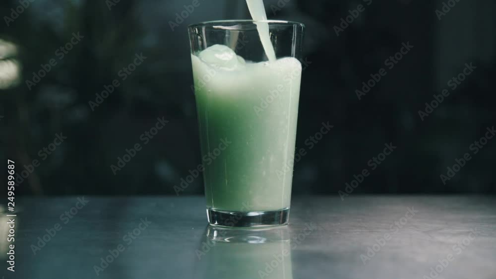 Pure green juice pouring into drink glass in slow motion Pure green juice pouring into drink glass in slow motion