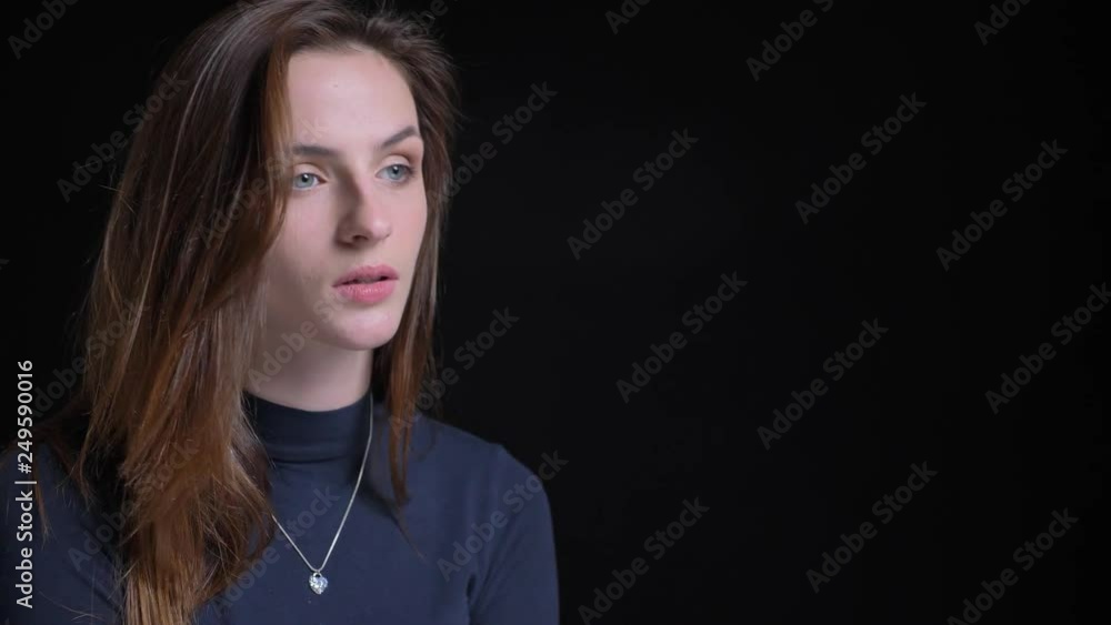 Close-up portrait of young and slim brunette caucasian girl fashionably and seriously posing into camera on black background. Close-up portrait of young and slim brunette caucasian girl fashionably and seriously posing into camera on black background.