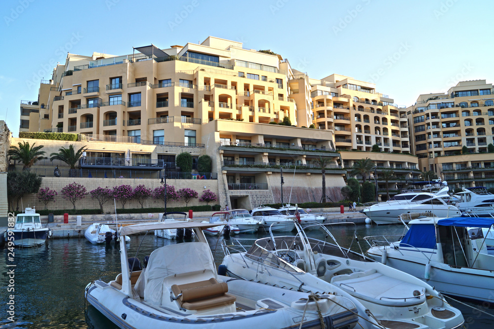 View of the sunset in marina with boats and hotel complex in the St. Julian's. Malta.