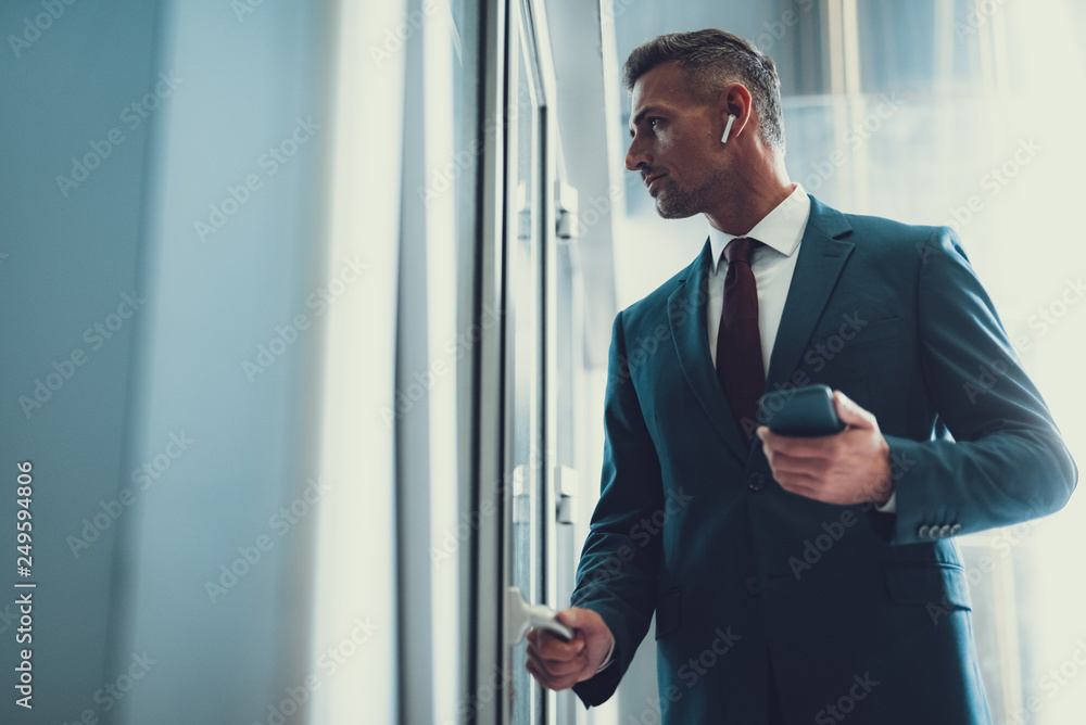 Man with telephone looking through glass door in office Man with telephone looking through glass door in office