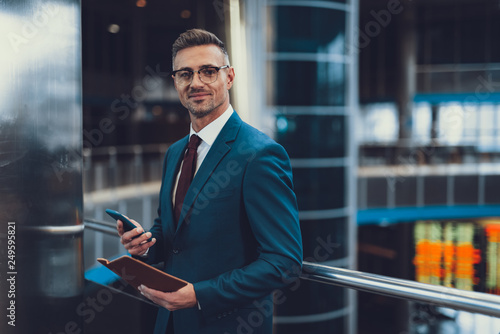 Tableau sur toile Man with documents and cellular looking at camera and smiling