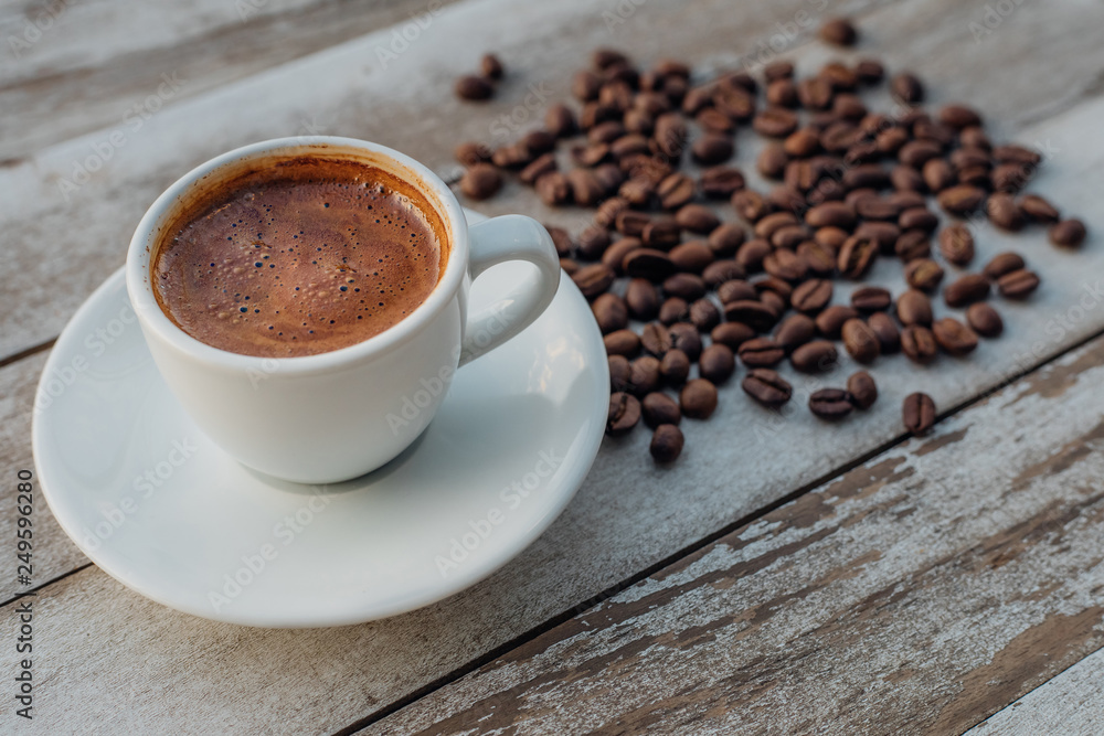 Obraz premium Turkish or Greek Hot Coffee on the white rustic wooden table with spilled coffee beans. This is traditional tasty refreshment greek or turkish coffee from greek or turkish cuisine culture