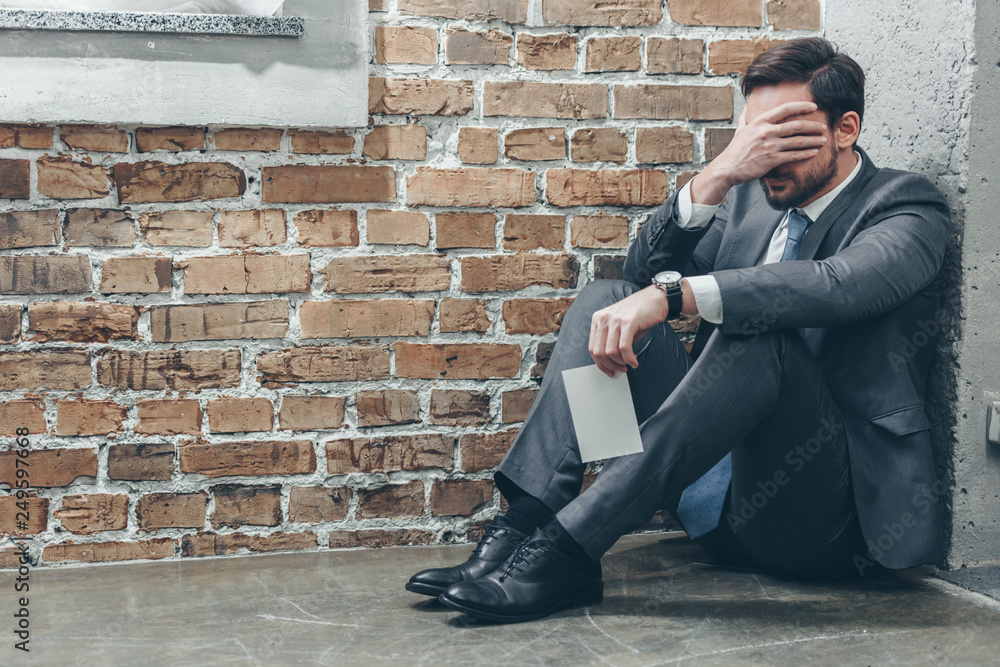 upset man sitting on floor in corner, holding photo and crying on brown textured background in room, grieving disorder concept upset man sitting on floor in corner, holding photo and crying on brown textured background in room, grieving disorder concept