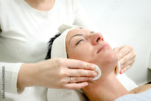 beautician worker gently massages face of female costumer in beauty salon