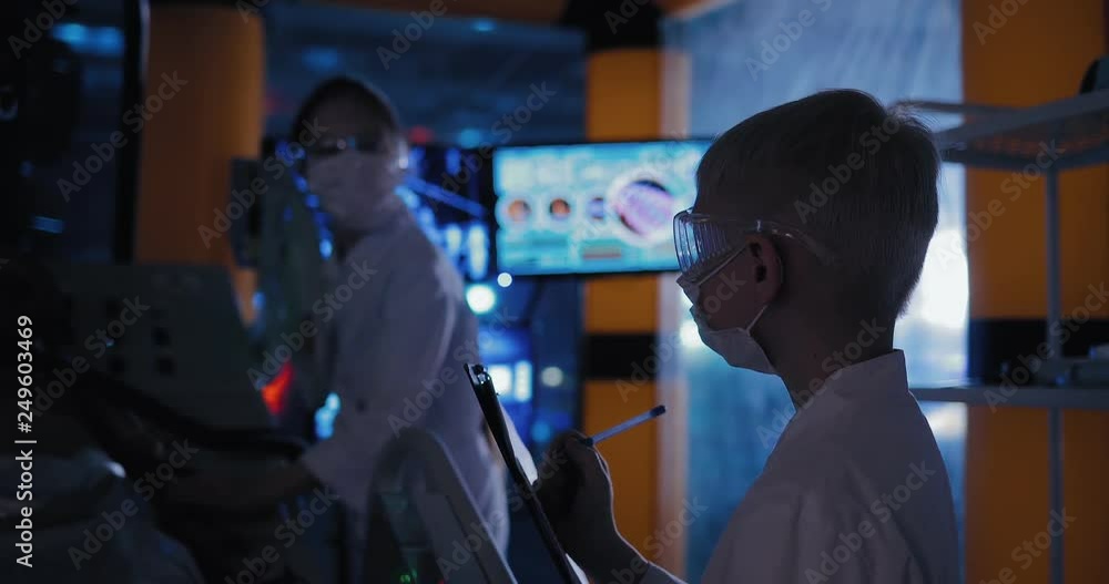 Group of scientists are examining humanoid. Alien lies on the table under the sensors of observation, you can see his breath. Group of scientists are examining humanoid. Alien lies on the table under the sensors of observation, you can see his breath.