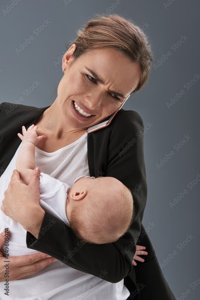 Charming mommy speaking at cellular and holding kin on hands Charming mommy speaking at cellular and holding kin on hands