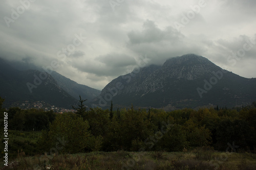 dramatic soft focus rainy foggy and cloudy European nature landscape of valley with big picturesque steep moutains in clouds background