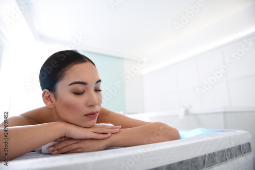 Relaxed asian lady enjoying on massage table