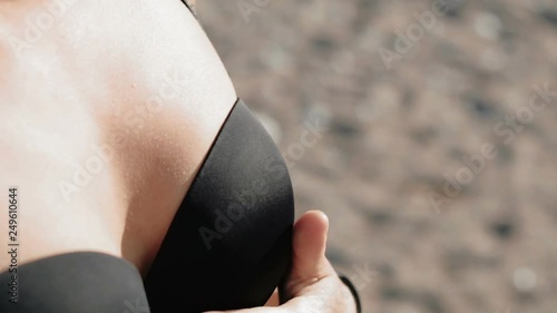 Beautiful female breasts in bra. The girl touches her on the beach