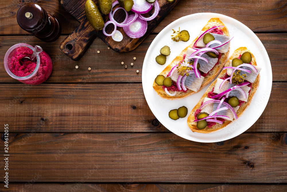 Delicious grilled sandwiches with herring, onion and beetroot sauce with horseradish on dark wooden rustic background. Danish cuisine. Top view Delicious grilled sandwiches with herring, onion and beetroot sauce with horseradish on dark wooden rustic background. Danish cuisine. Top view
