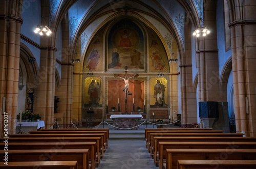 Trier / Germany - February 9 / 2019: crucifixtion statue of jesus in front of benchs at Saint Gangolf's church 