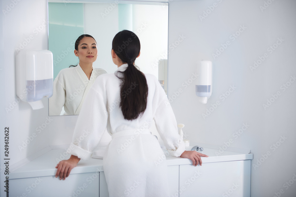 Fototapeta premium Asian lady look at mirror with satisfaction