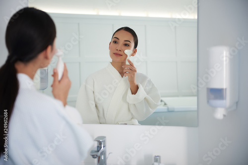 Young asian lady cleaning face with brush