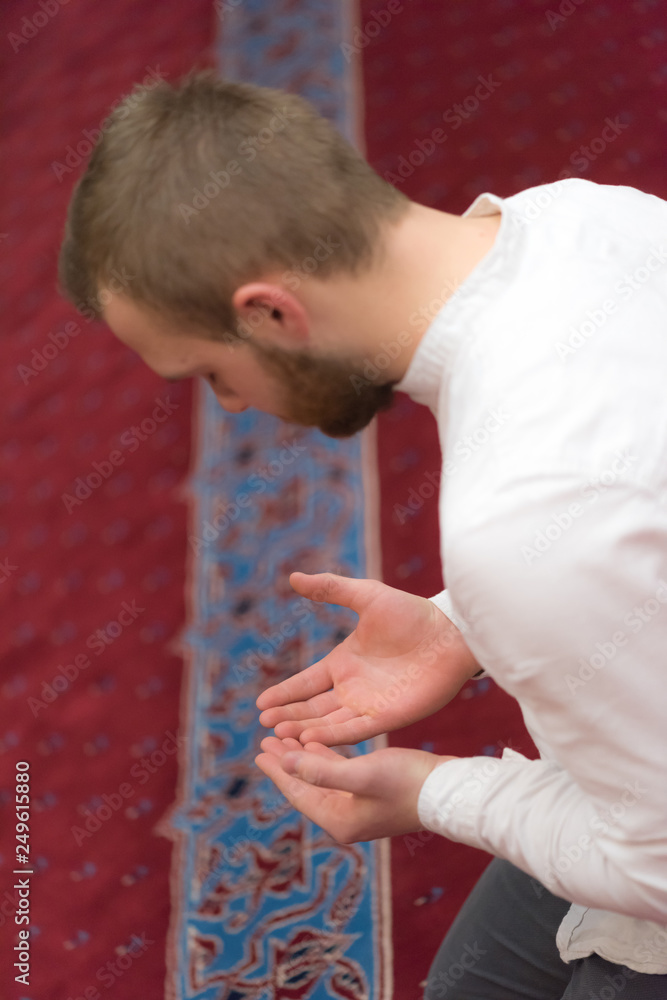 Young religious european muslim man praying inside the beautiful big mosque.