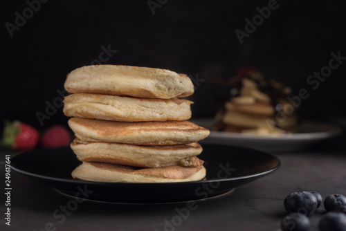 Stack of delicious homemade pancakes on a black plate with fruits. Horizontal. Copyspace. Closeup