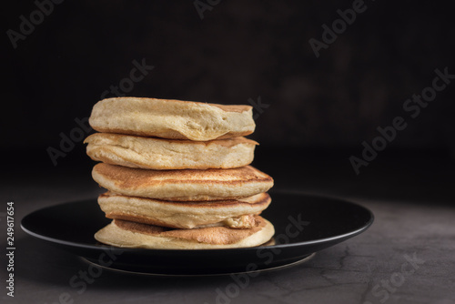 Stack of delicious homemade pancakes on a black plate. Horizontal. Copyspace