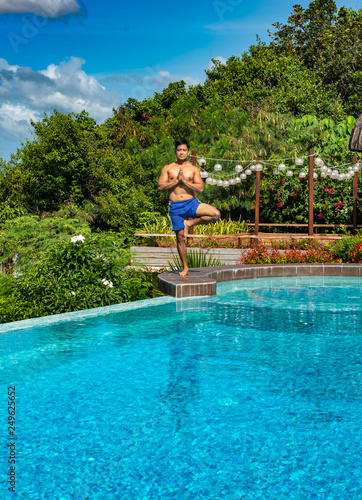 Filipino male doing yoga poses poolside