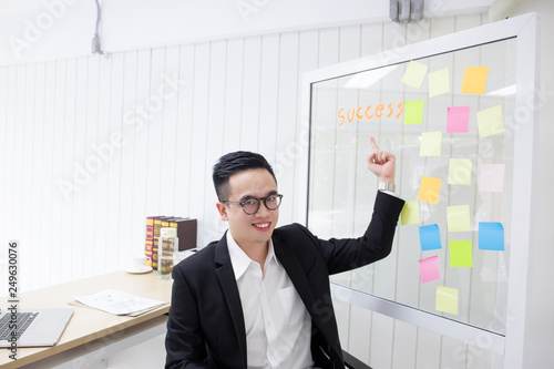 Portrait of smart young business man pointing at glass board.